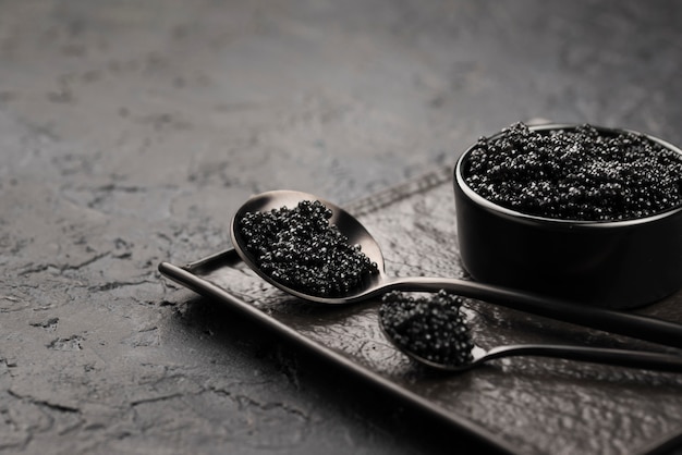 Caviar preto em uma tigela com colheres e concha