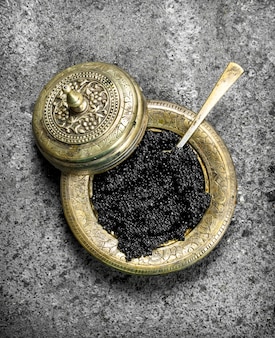 Caviar preto na tigela velha. sobre fundo rústico.