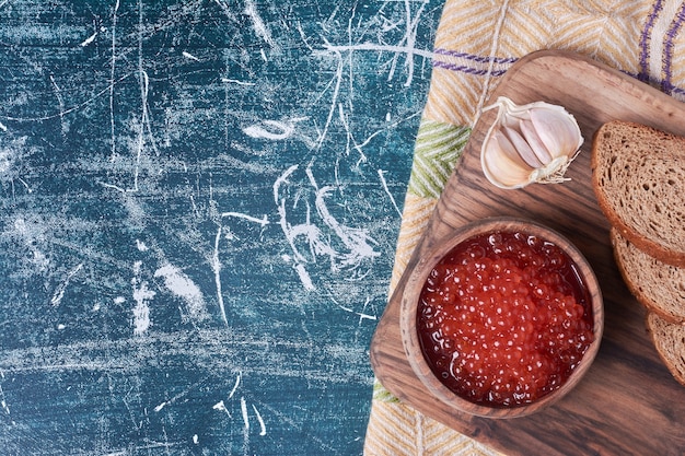 Foto grátis caviar vermelho na placa de madeira com fatias de pão.