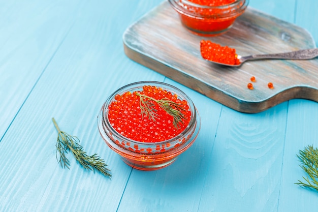 Caviar vermelho na tigela de vidro e em uma colher, vista superior