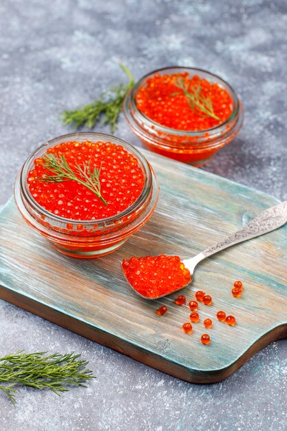 Caviar vermelho na tigela de vidro e em uma colher, vista superior