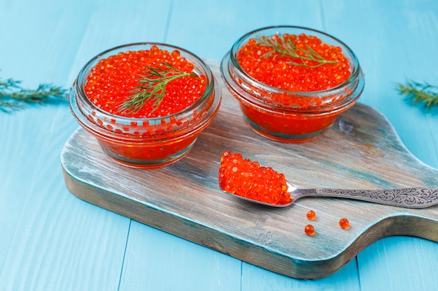 Caviar vermelho na tigela de vidro e em uma colher, vista superior