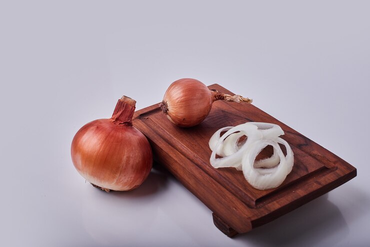 Foto grátis cebolas inteiras e fatiadas em uma placa de madeira
