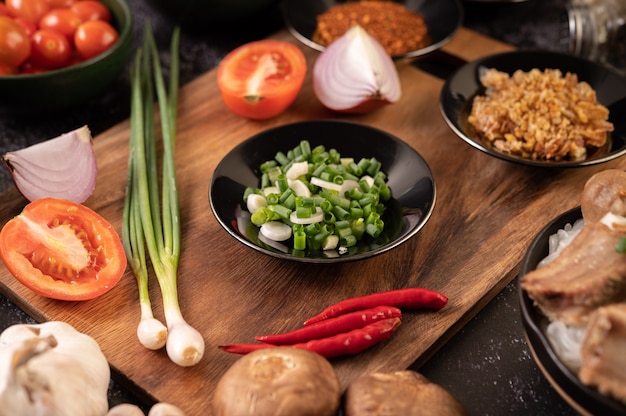 Foto grátis cebolinha picada em uma placa preta com pimenta, tomate e alho