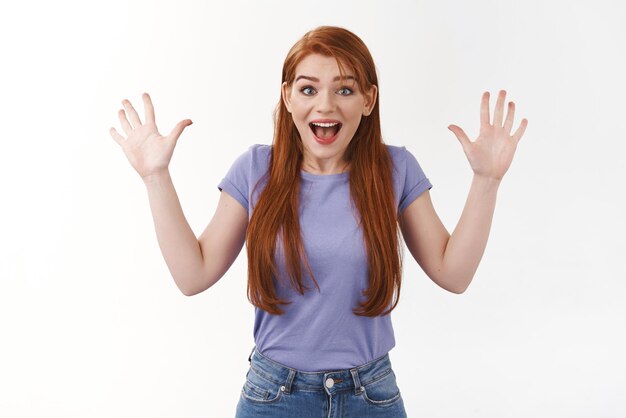 Celebração surpresa e conceito de felicidade Menina ruiva alegre com longos cabelos ruivos levantando as mãos triunfando animado sorrindo ofegante fascinado receber boas notícias incríveis fundo branco