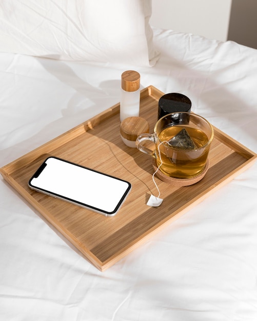 Celular e copo de chá em cima da cama