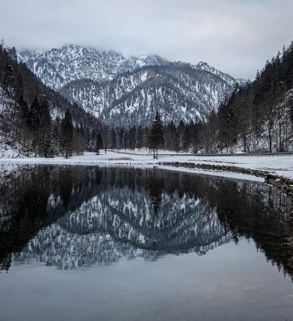 Foto grátis cena hipnotizante de montanhas nevadas rochosas sob um céu nebuloso refletindo em um lago de água