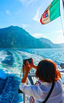 Cenário com turista mulher no barco durante a excursão de cruzeiro no mar tirreno na cidade de positano na costa amalfitana, itália no verão. vista perto de salerno. férias e feriado. litoral amalfitana.