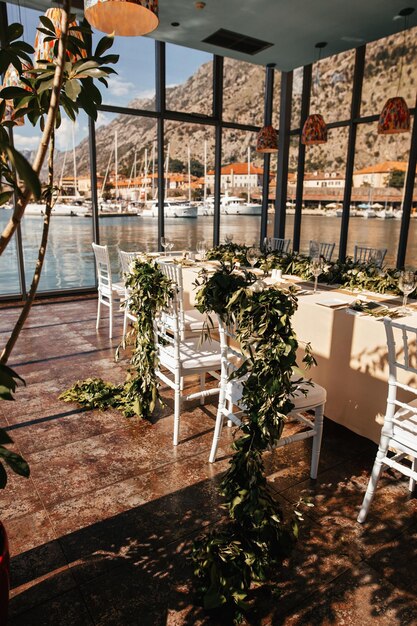 Cenário de mesa com cadeiras decoradas de recém-casados no salão de recepção de casamento