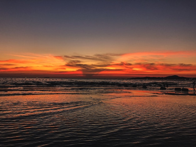 Cenário do pôr do sol na praia com ondas calmas do oceano