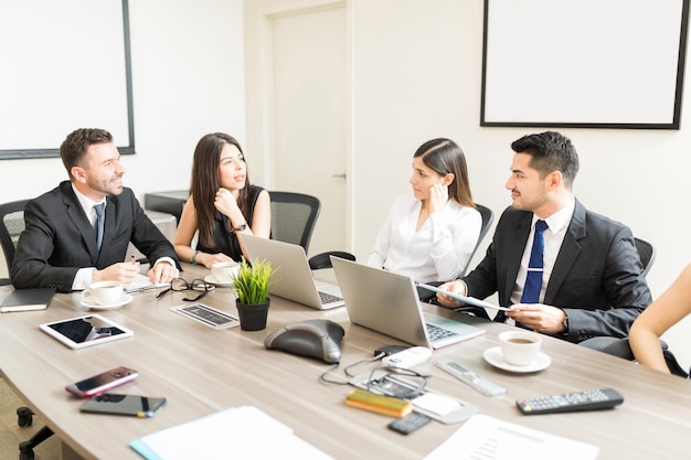 Ceos da empresa falando sobre o acordo de fusão enquanto estão sentados na mesa no escritório