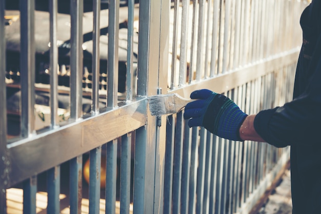 Cerca de pintura de trabalhador de construção em casa