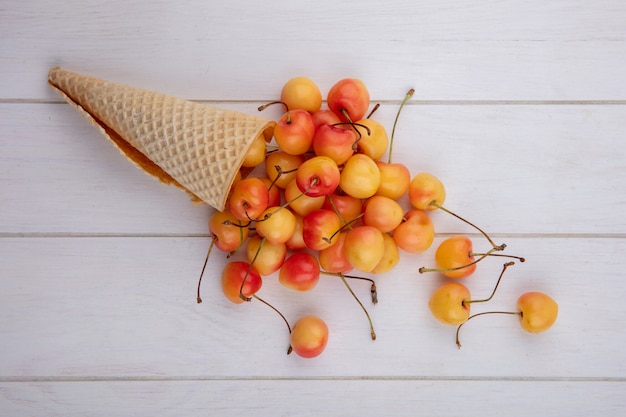 Cereja branca de cima com um cone de waffle em uma mesa branca