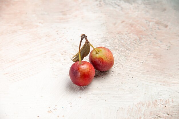 Cerejas de cima para cima, cerejas vermelhas e amarelas na mesa rosa-branco-cinza