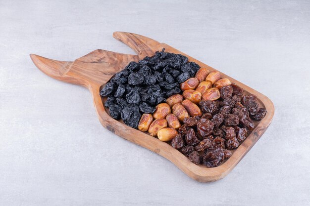 Cerejas secas, frutas vermelhas e tâmaras em uma bandeja de madeira. Foto de alta qualidade