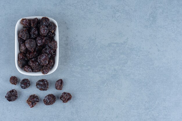 Cerejas secas na tigela, na mesa de mármore.