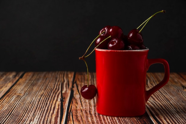 Cerejas vermelhas em um copo vermelho na mesa