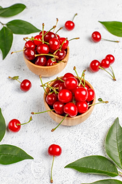 Cerejas vermelhas na tigela de prato na mesa cinza