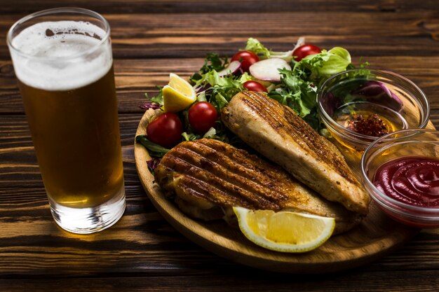 Cerveja e molho perto de frango e salada