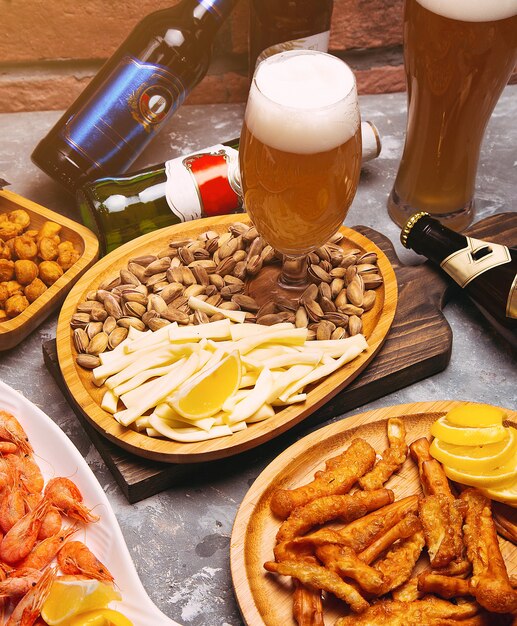 Cerveja e petiscos de cerveja pilsen na tabela de madeira. Nozes, queijo chips, pistachios, crevettes