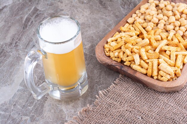 Cerveja e prato de biscoitos e ervilhas na superfície de mármore. Foto de alta qualidade