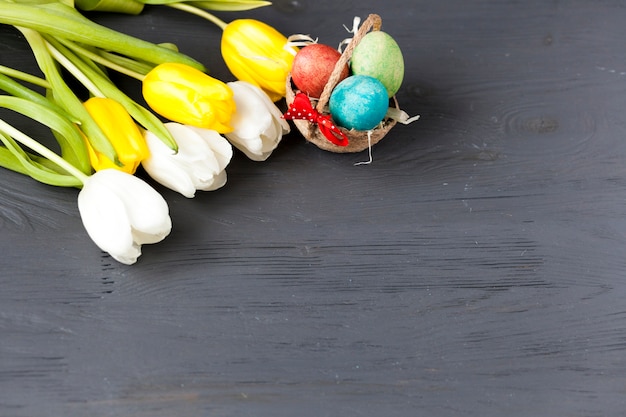 Cesta com ovos perto de um monte de tulipas