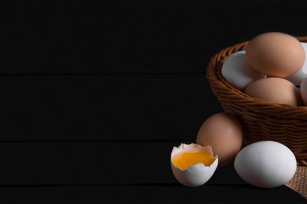 Cesta de vime com ovos de galinha crus na superfície de madeira escura. Foto de alta qualidade