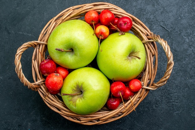 Cesta de vista superior com frutas, maçãs e cerejas doces na árvore de frescor da composição de frutas e frutas da mesa escura