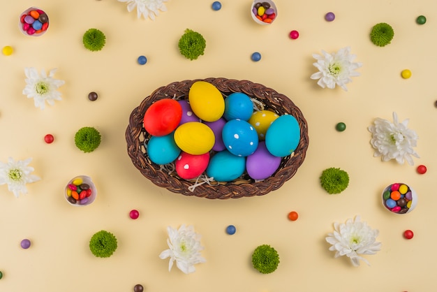 Cesta grande com ovos de Páscoa coloridos na mesa bege