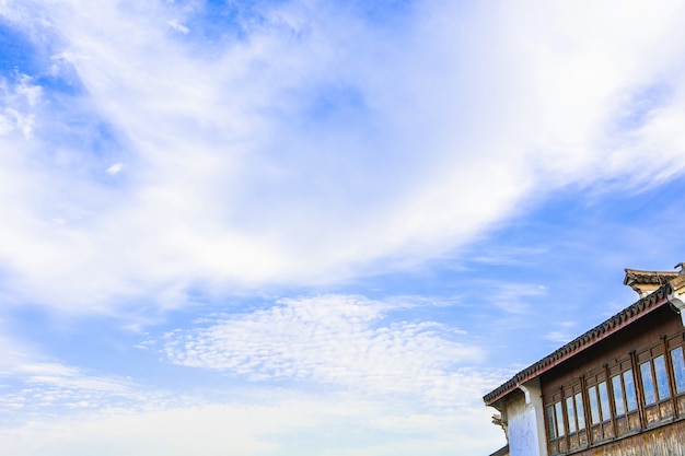 Céu azul com nuvens e telhado