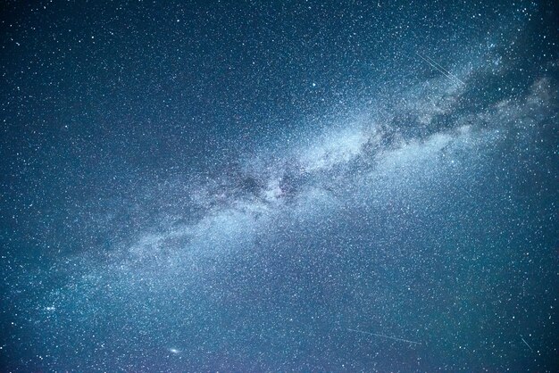 Céu noturno vibrante com estrelas, nebulosa e galáxia.