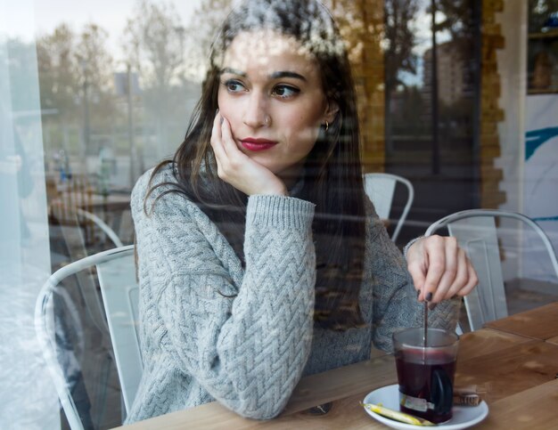 Chá bebendo bonito da mulher nova em uma cafetaria.