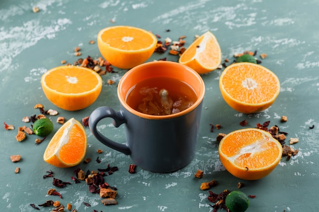 Foto grátis chá com ervas secas, laranjas, limas em um copo na superfície de gesso