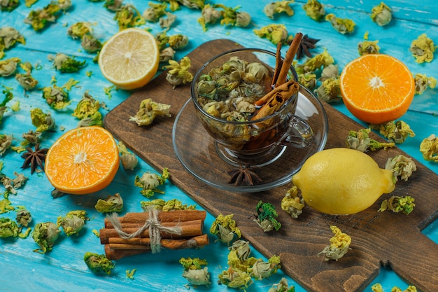 Chá com especiarias, laranja, limão, ervas secas em uma caneca azul e tábua de cortar