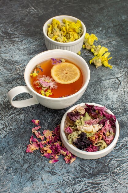 chá de ervas com flores secas e um prato em fundo cinza