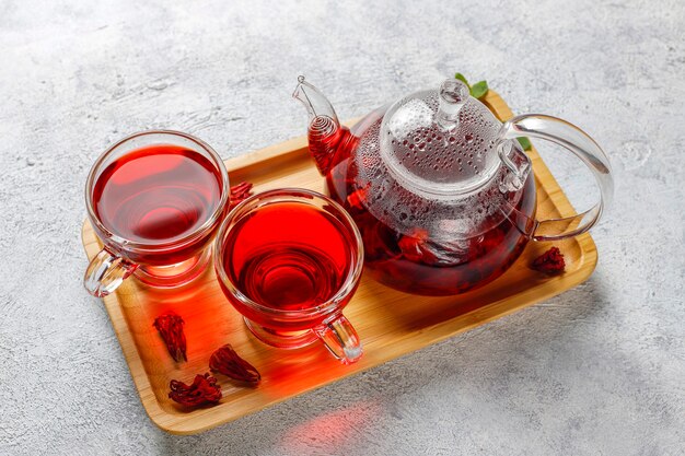 Chá de hibisco quente em uma caneca de vidro e bule de vidro.