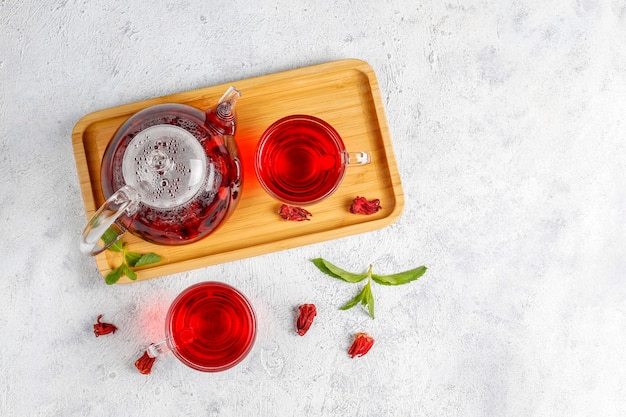 Chá de hibisco quente em uma caneca de vidro e bule de vidro.