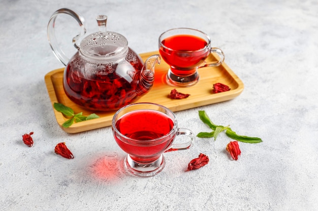 Chá de hibisco quente em uma caneca de vidro e bule de vidro.