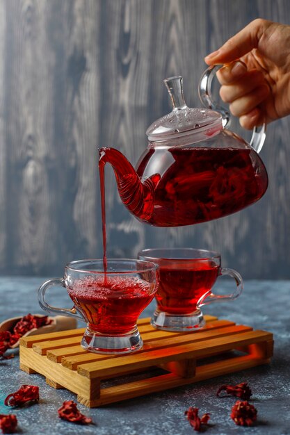 Chá de hibisco quente em uma caneca de vidro e bule de vidro.