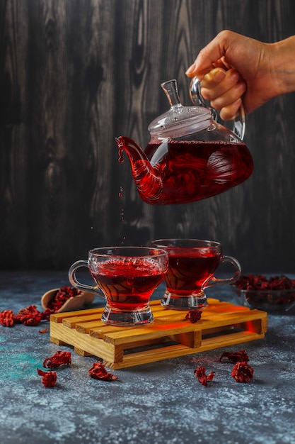 Chá de hibisco quente em uma caneca de vidro e bule de vidro.