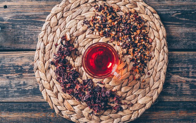 Chá em um trivet com vista superior de ervas de chá em um fundo escuro de madeira