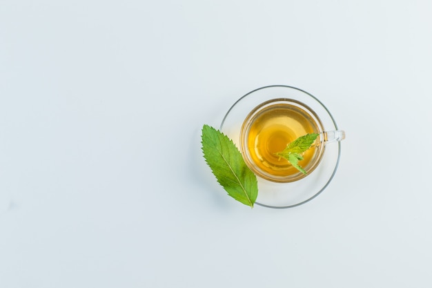 Chá em uma caneca com ervas planas sobre um fundo branco