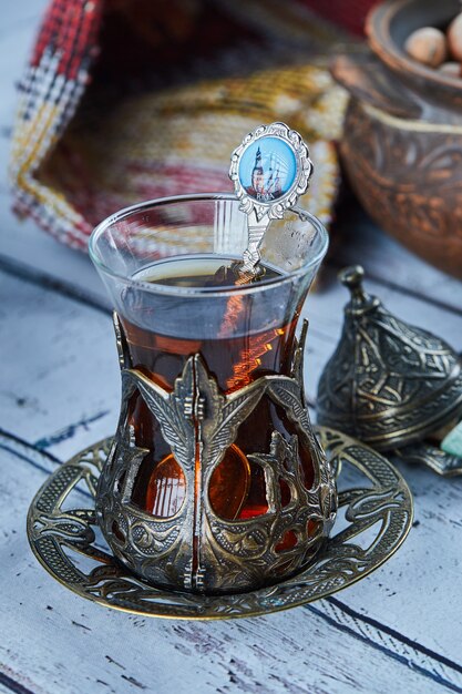 Chá preto em uma tradicional xícara de vidro e biscoitos na mesa de madeira azul