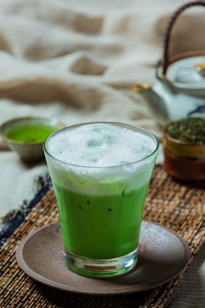 Chá verde gelado em um copo alto com creme coberto com chá verde gelado. Decorado com chá verde em pó.
