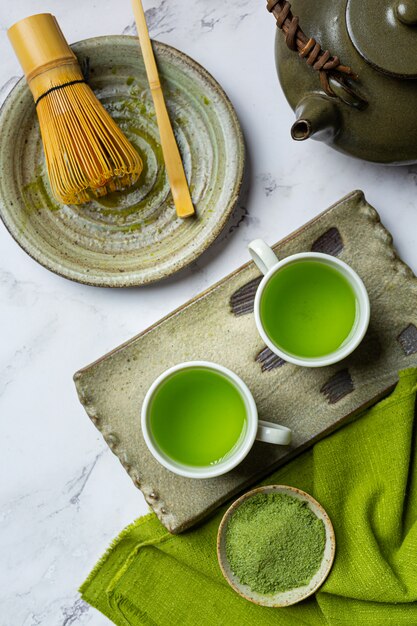 Chá verde quente em um copo com creme coberto com chá verde, decorado com pó de chá verde.