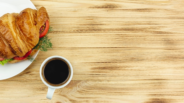 Chapa branca com um sanduíche e uma xícara de café