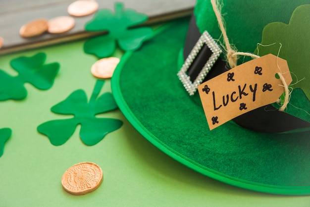Chapéu de Saint Patricks com tag perto de moedas e trevos decorativos