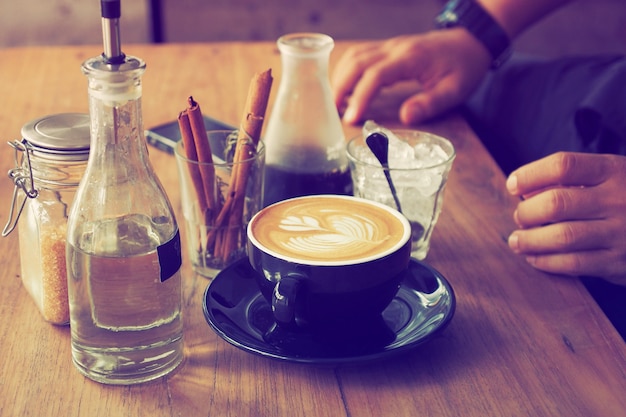 Chávena de café com uma garrafa de água e um copo com varas de canela