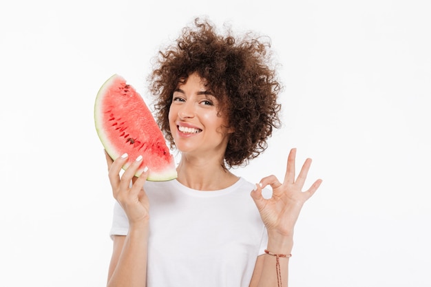 Foto grátis cheerfuwoman feliz com cabelos cacheados, segurando a fatia de melancia