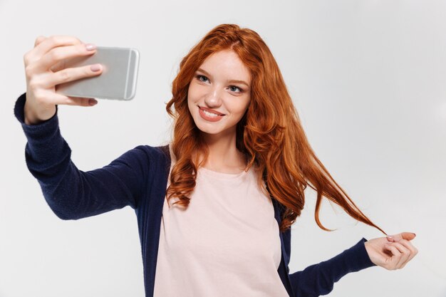 Cheerul jovem ruiva fazer selfie por telefone móvel.